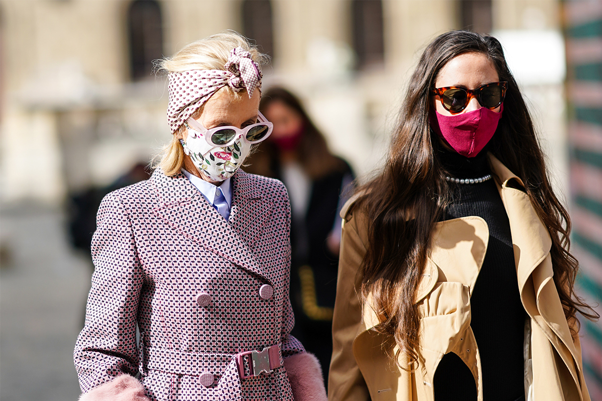 A guest wears a bandanna, sunglasses, a floral print face mask, a shirt, a tie, a double breasted trench coat ; a guest (R) wears a black wool turtleneck pullover, pearl necklace, a beige trench coat, outside Gabriela Hearst, during Paris Fashion Week - Womenswear Spring Summer 2021, on October 04, 2020 in Paris, France.